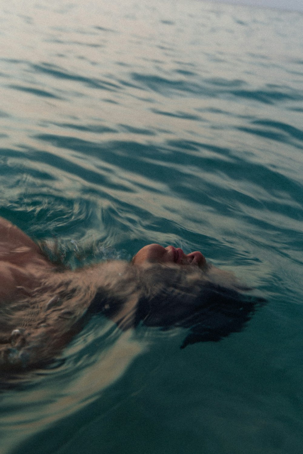 a man swimming in the ocean with his head above the water