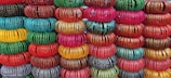 Close-up of colorful handmade bangles stacked on a wooden table.