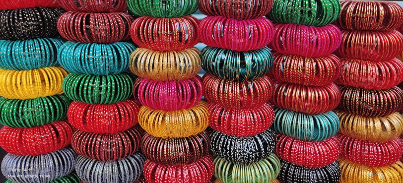Close-up of maroon and gold bangles stacked gracefully on a wooden display.