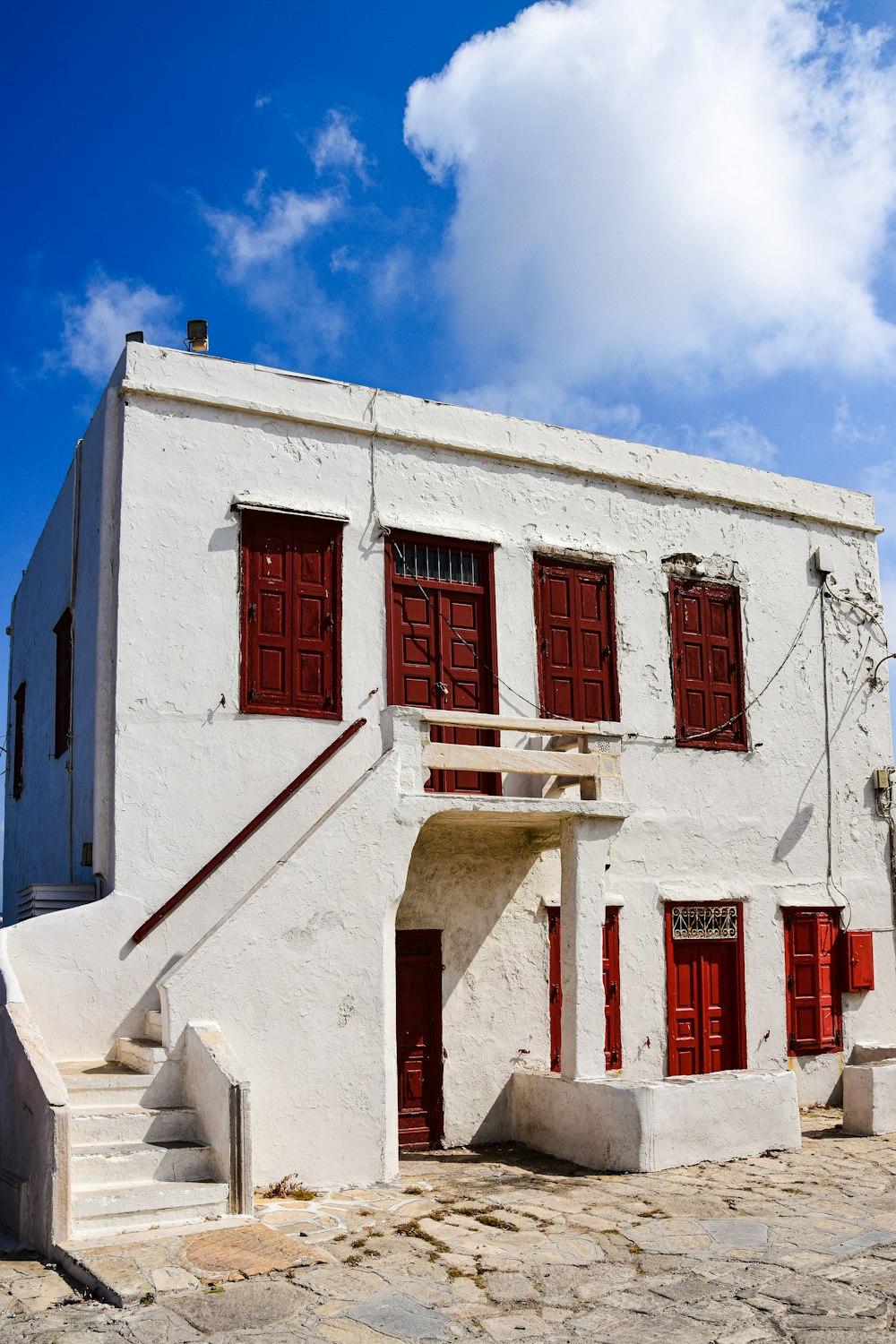 a white building with red shutters and a staircase