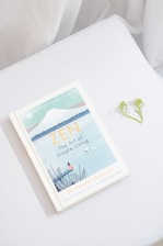 a book sitting on top of a bed next to a flower