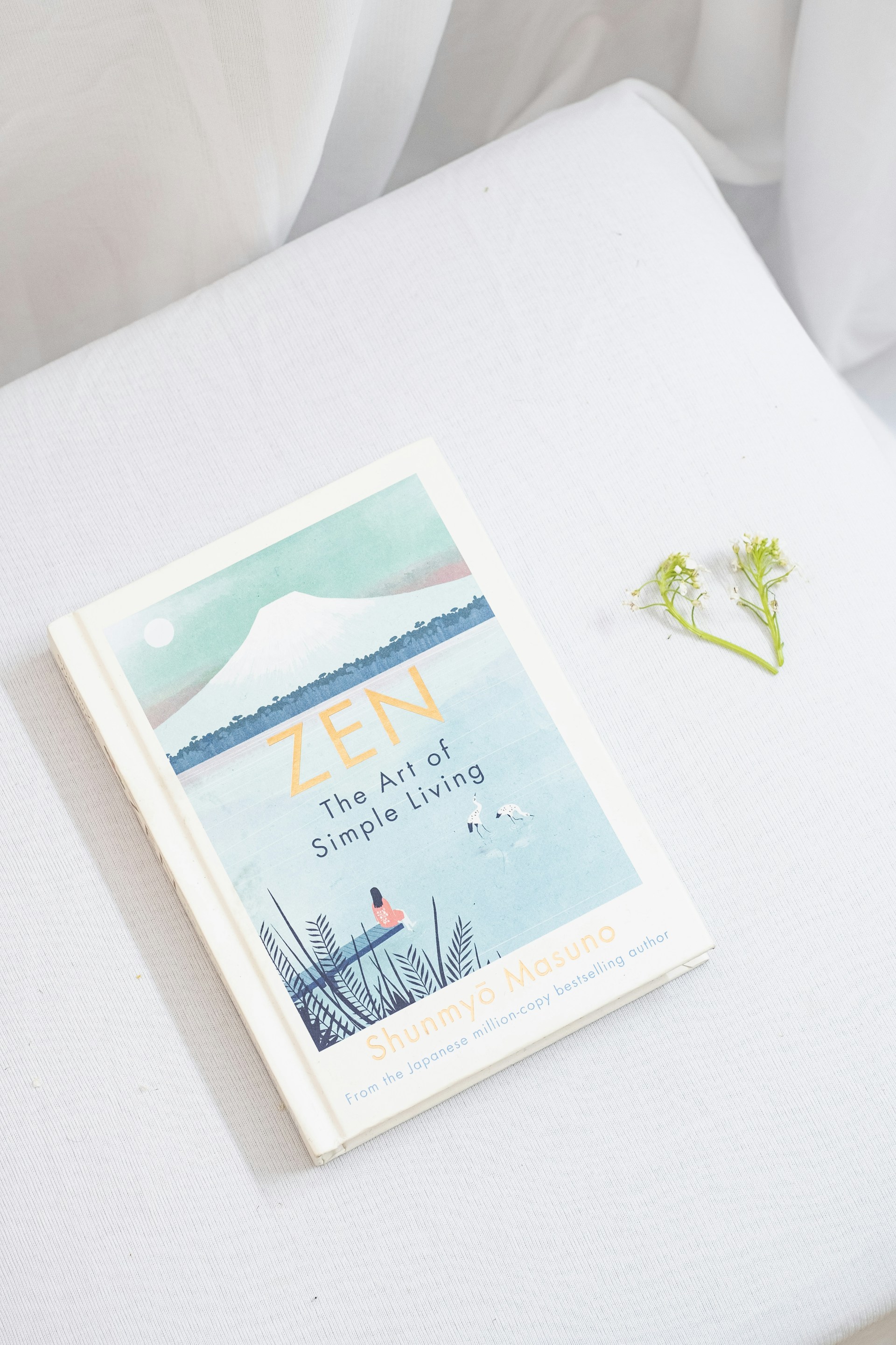 a book sitting on top of a bed next to a flower