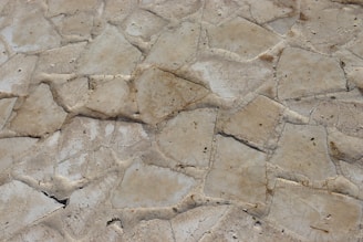 Hands running over the textured surface of a rugged, earthy-toned natural stone tile.