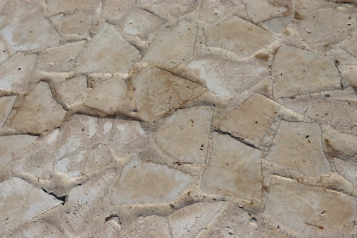 Hands running over the textured surface of a rugged, earthy-toned natural stone tile.