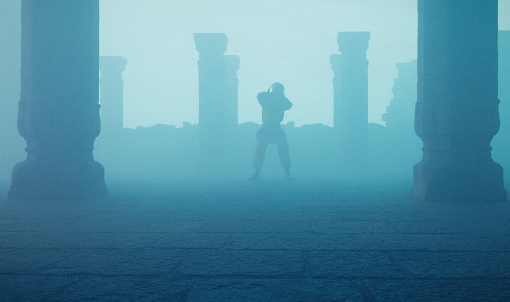 Una persona parada frente a pilares en un área con niebla
