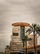 a tall building with a yellow roof and palm trees in front of it