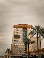 a tall building with a yellow roof and palm trees in front of it