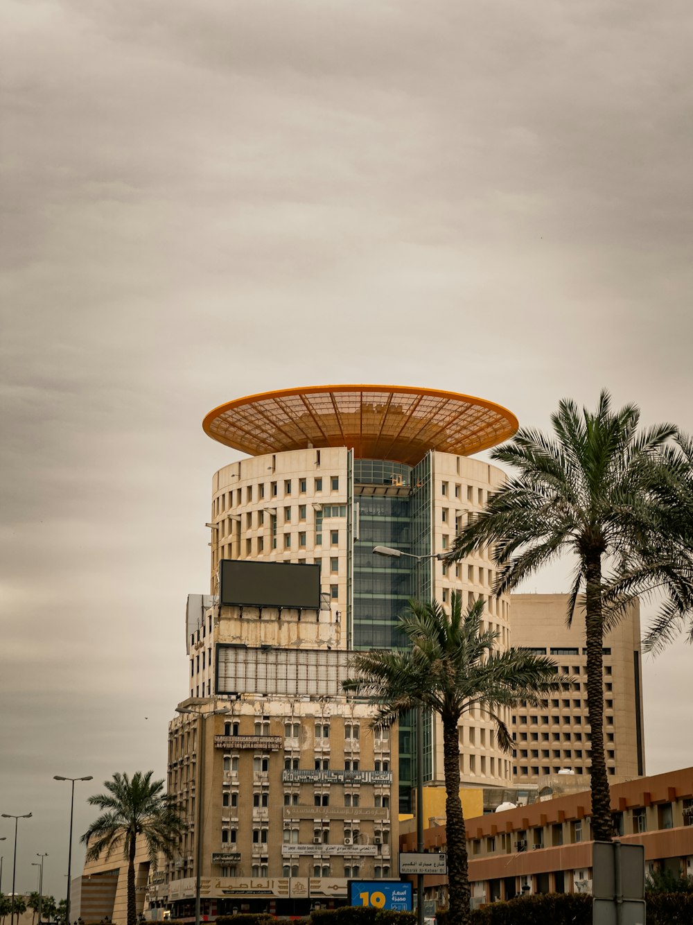 a tall building with a yellow roof and palm trees in front of it