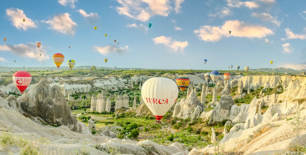 a group of hot air balloons flying over a valley