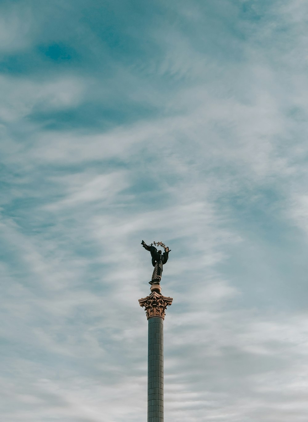 una statua in cima a un alto palo di metallo