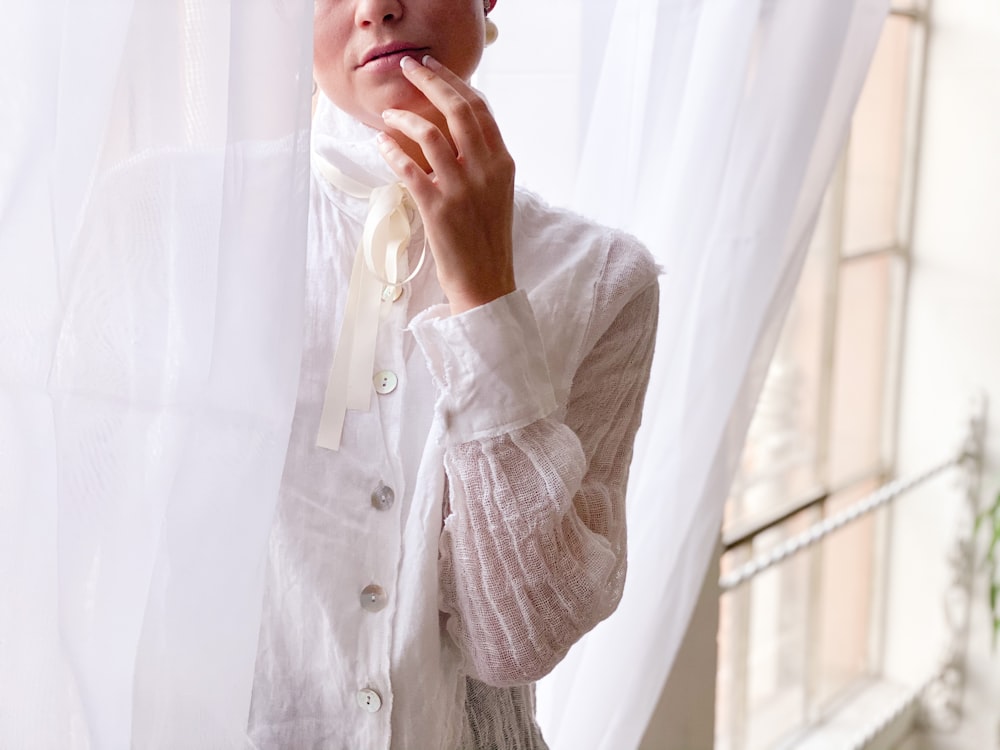 a woman standing in front of a white curtain