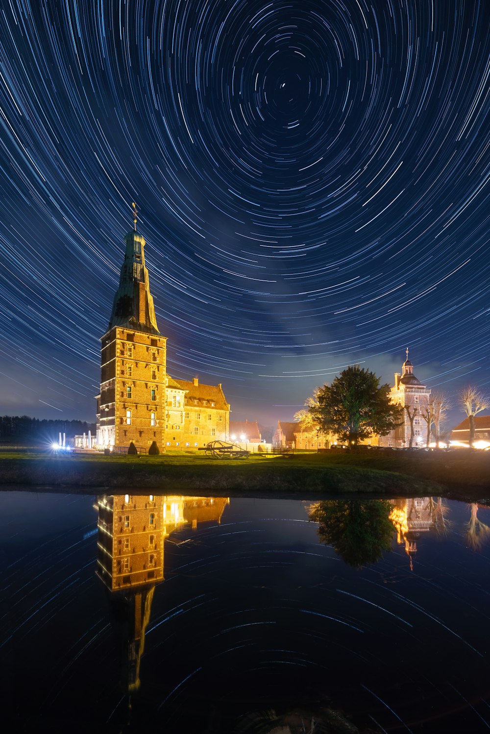 a star trail over a lake with a building in the background