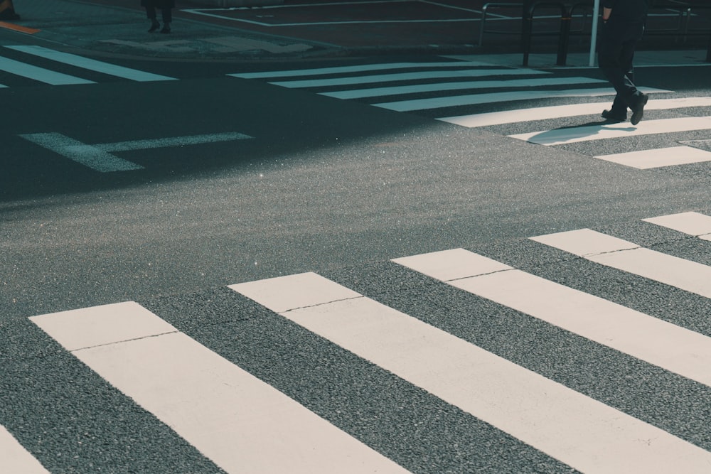 a person walking across a cross walk in the middle of a street