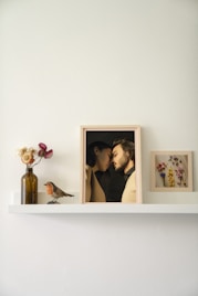 a shelf with a picture of two people and a vase of flowers