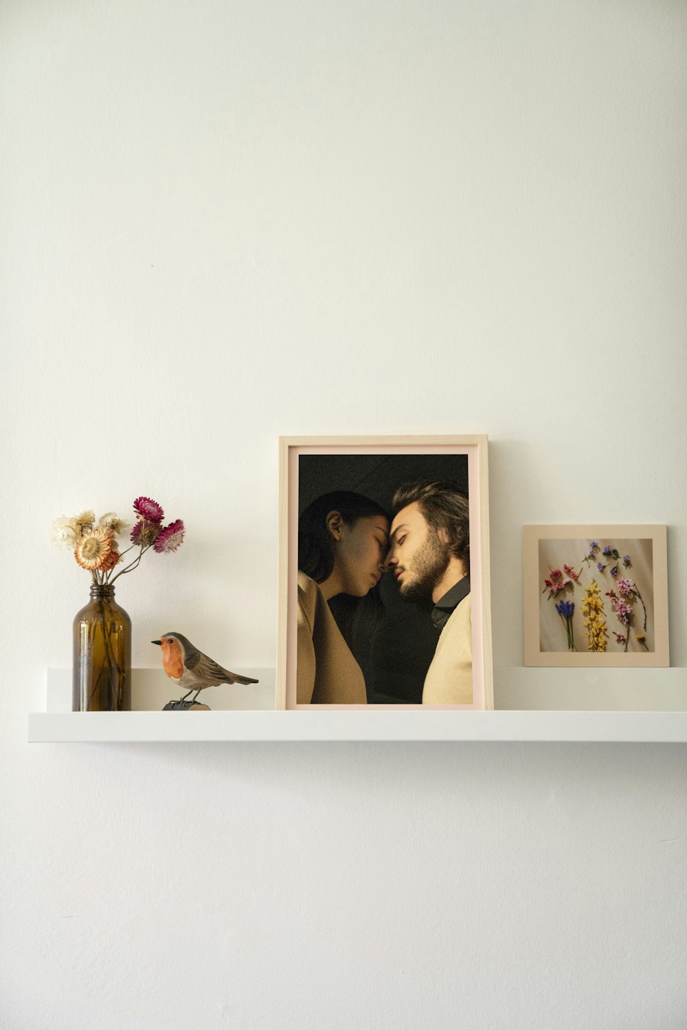 a shelf with a picture of two people and a vase of flowers