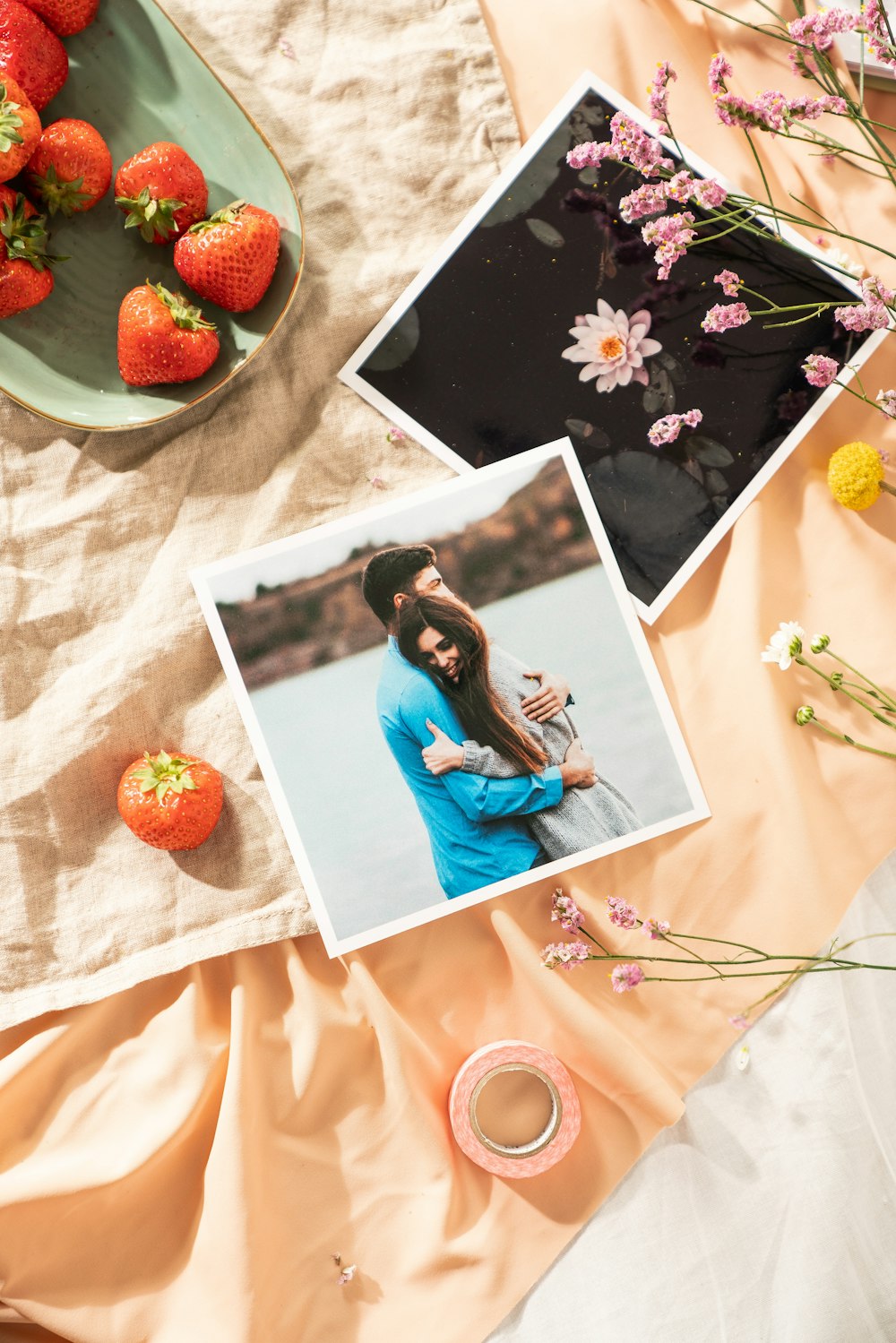 a table topped with pictures and strawberries next to a bowl of strawberries