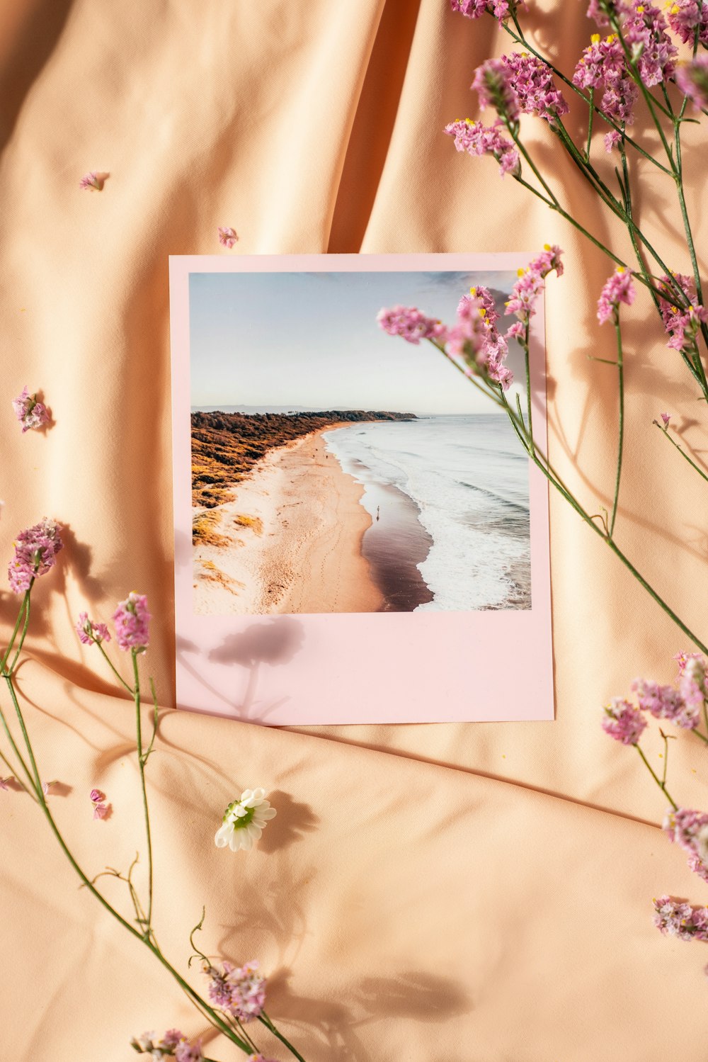 Una tarjeta con una foto de una playa y flores