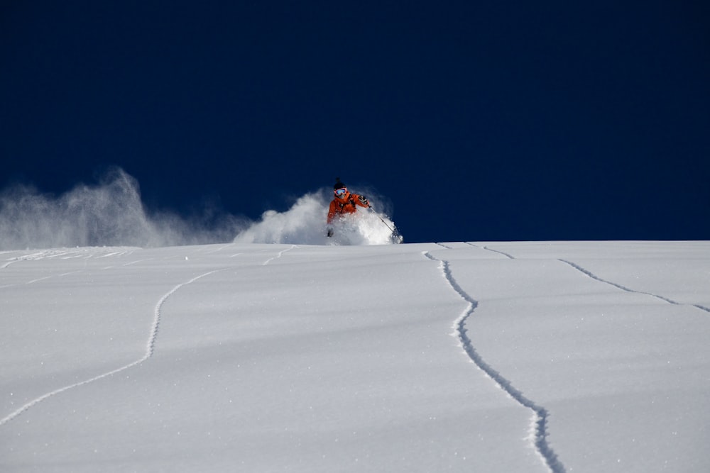 a person riding a snowboard down a snow covered slope