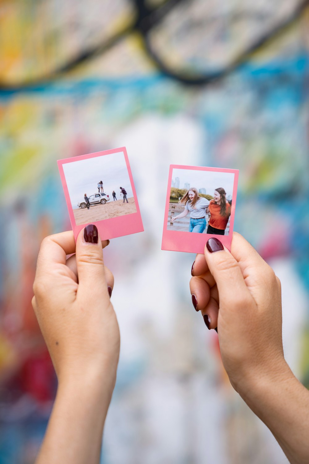 two hands holding up photos of people on the beach