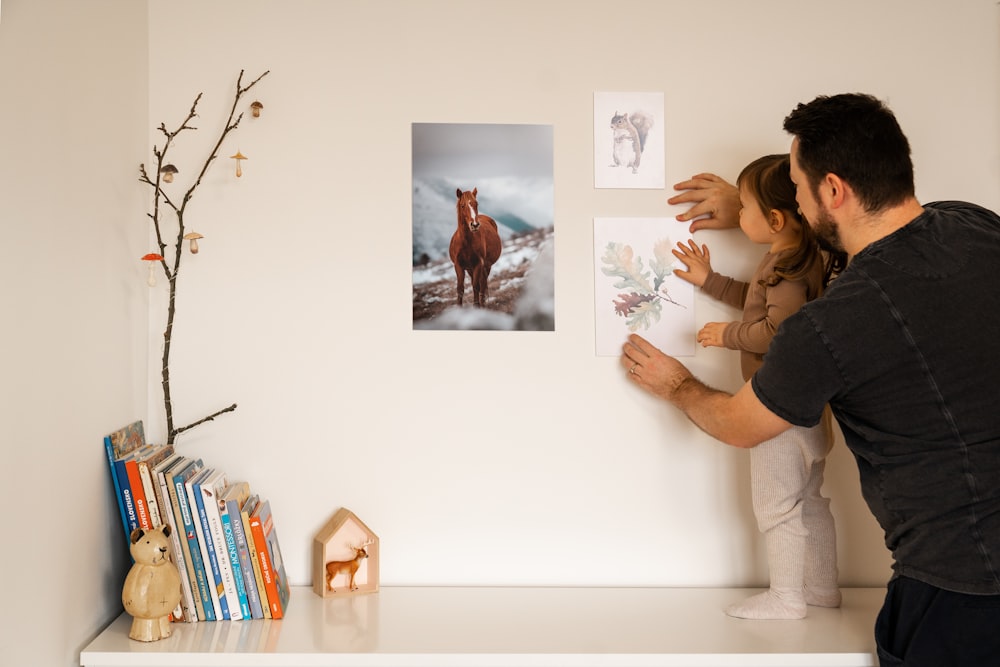 Un homme et une petite fille regardant des photos sur un mur