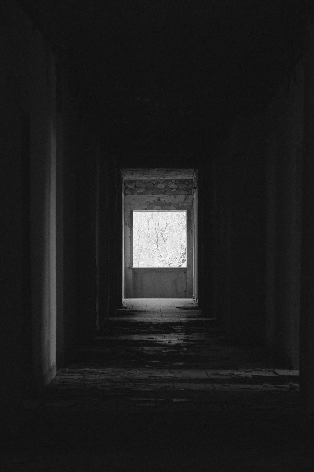 a long dark hallway with a window in the middle