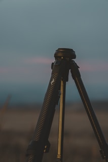 A sleek tripod standing on a wooden floor with soft natural light highlighting its sturdy build