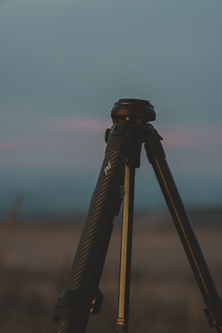 A sleek tripod standing on a wooden floor with soft natural light highlighting its sturdy build