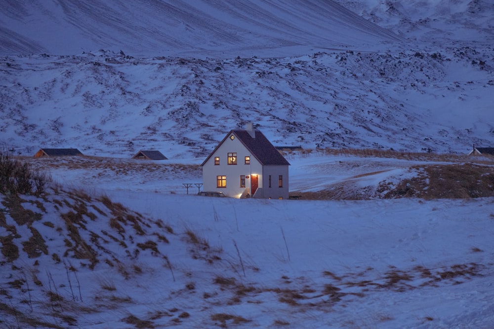 a small white house in the middle of a snowy field