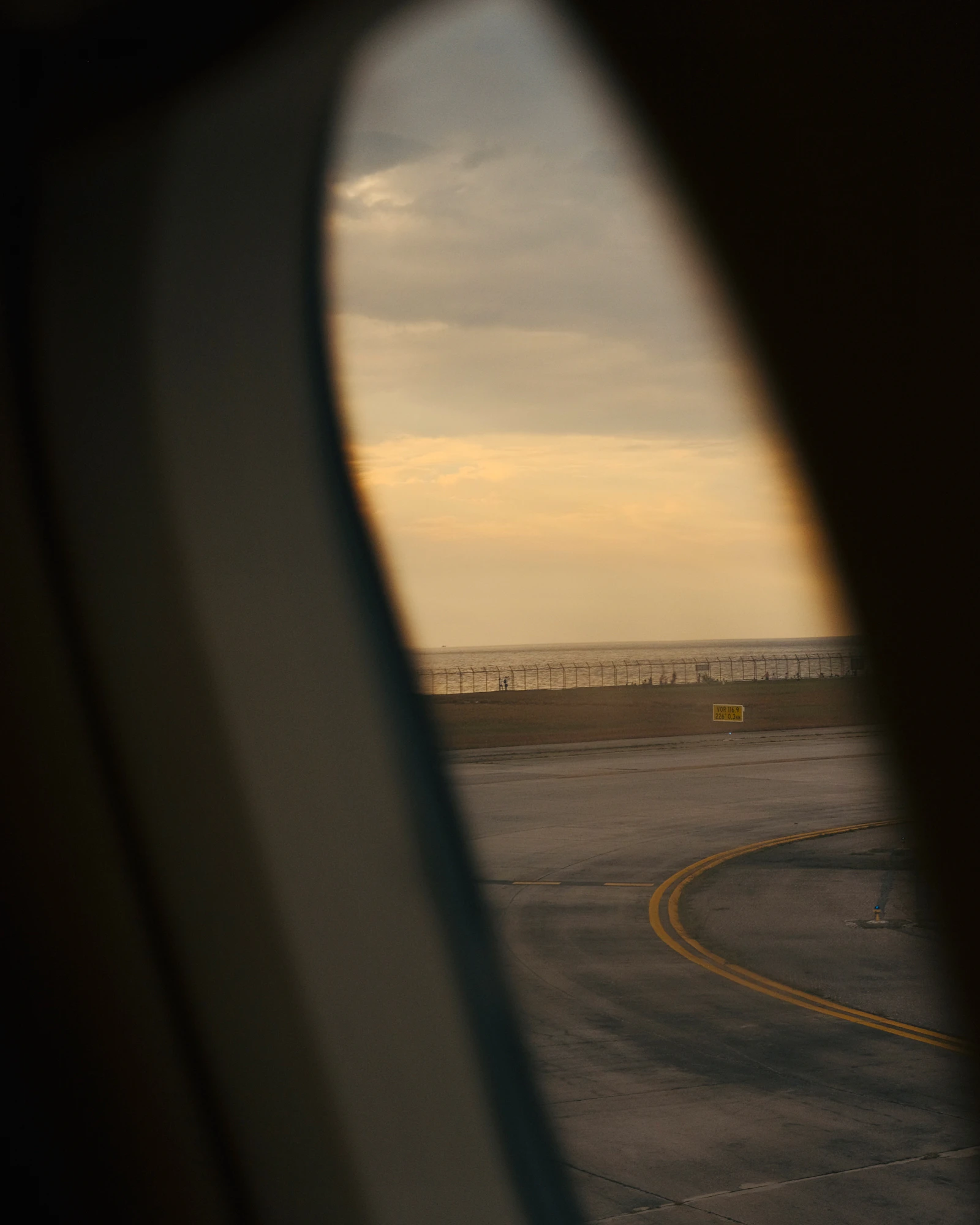 A view of an airport runway seen through an airplane window before takeoff