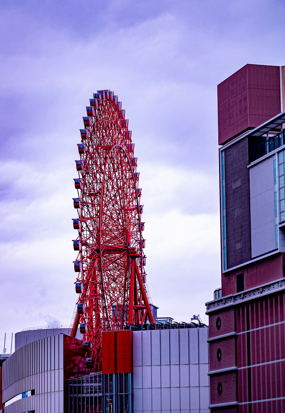 a red ferris wheel sitting next to a tall building