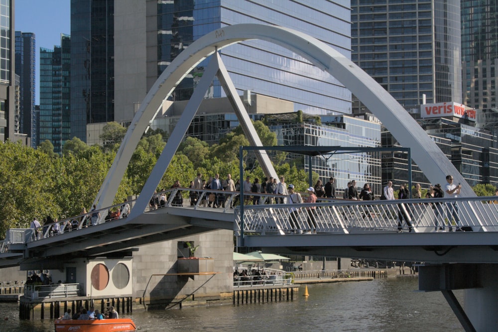 a group of people walking across a bridge over a river