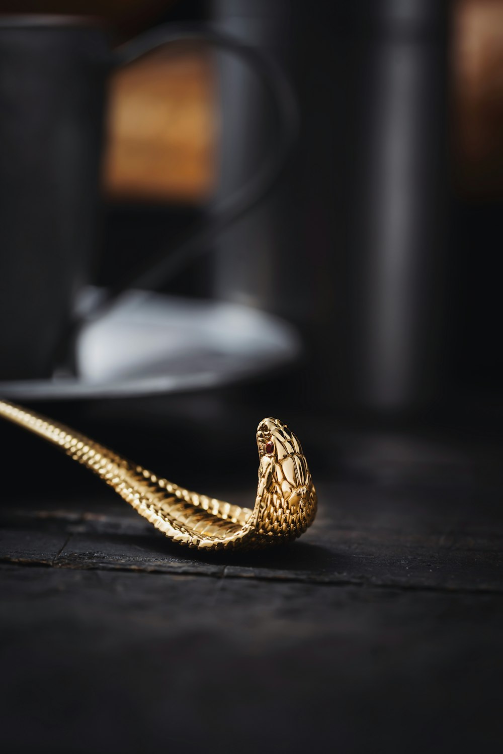 a golden snake on a table next to a coffee cup