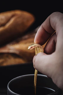 Close-up of hands clutching a gold chain, dimly lit against a textured dark backdrop with subtle smoke curling around.