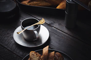 Set of copper silverware resting on a rustic linen cloth beside a steaming cup