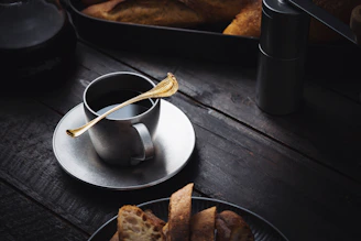 Set of copper silverware resting on a rustic linen cloth beside a steaming cup