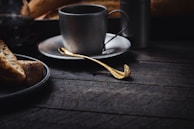 A rustic kitchen scene featuring a wooden tray holding freshly baked bread and a steaming cup of tea.