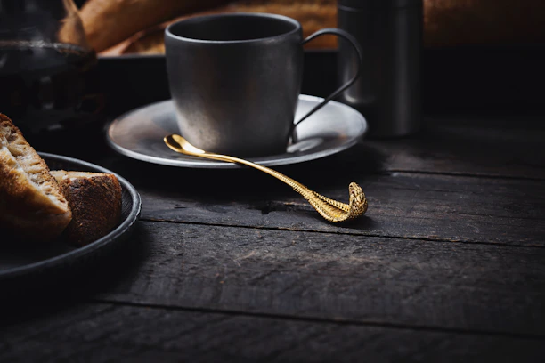A cozy kitchen scene with a dúocucharas spoon and fork resting on a rustic wooden table beside a steaming cup of tea.