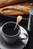Personalized coffee cup with custom printing beside a matching gold spoon.