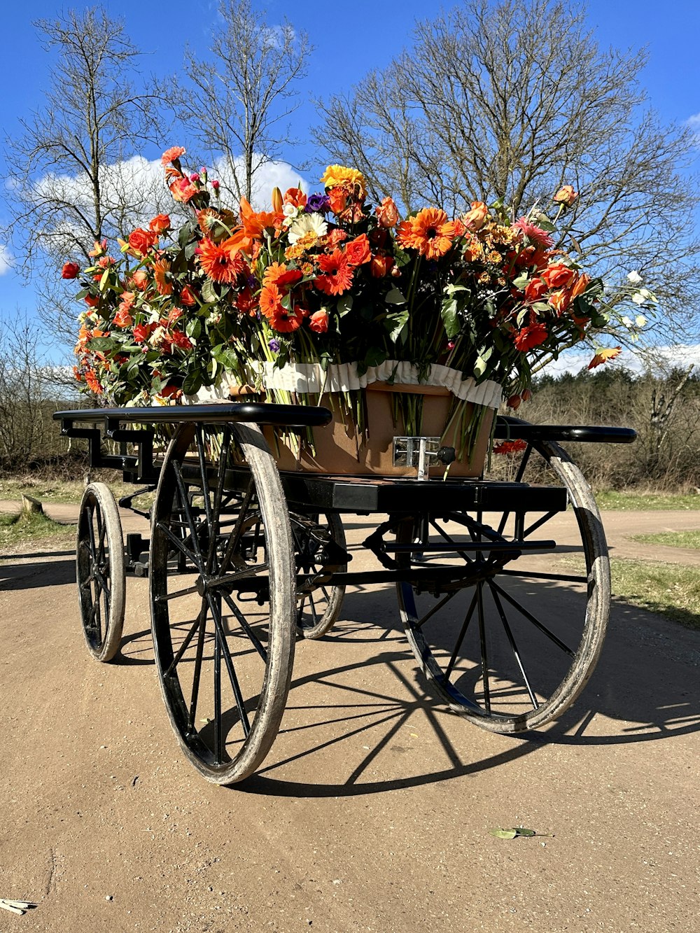 a wagon filled with flowers sitting on top of a dirt road