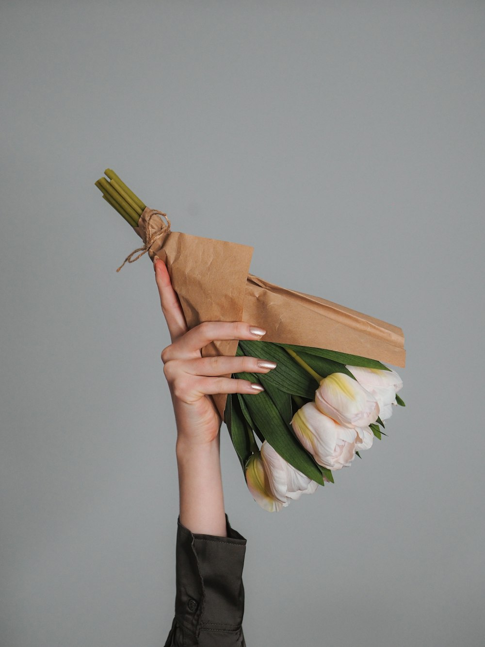 a woman holding a brown paper bag with flowers in it