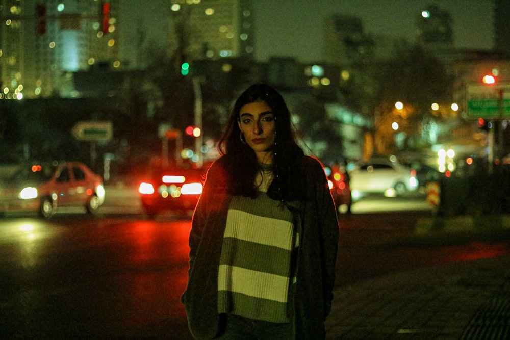 a woman standing on a city street at night