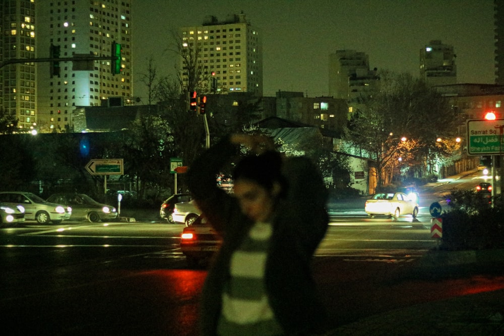 a woman walking across a street at night