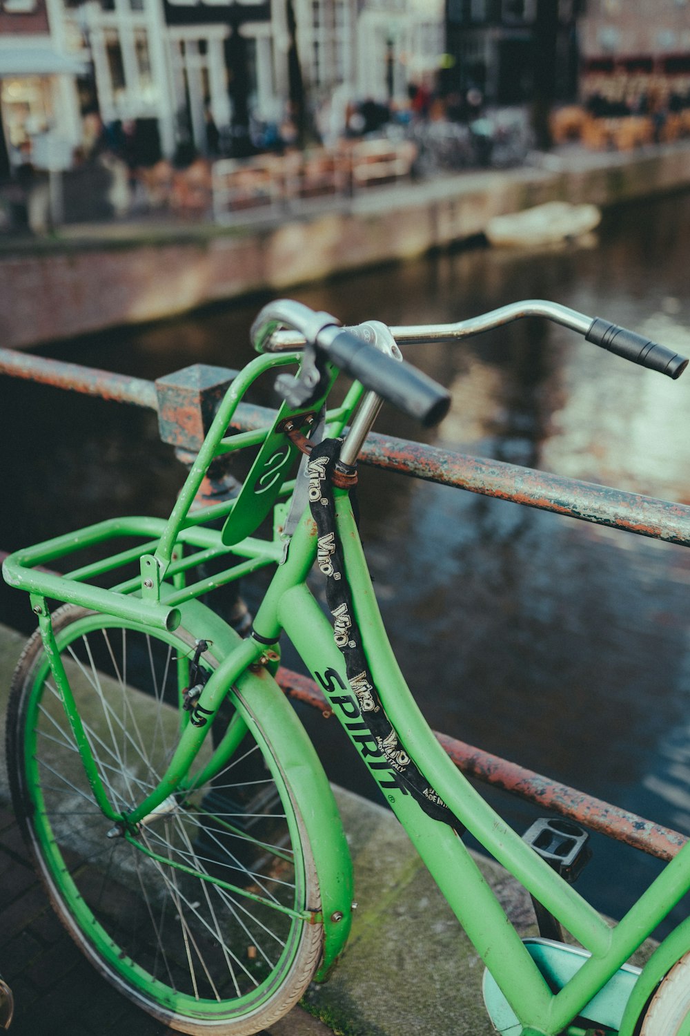 a green bicycle parked next to a river