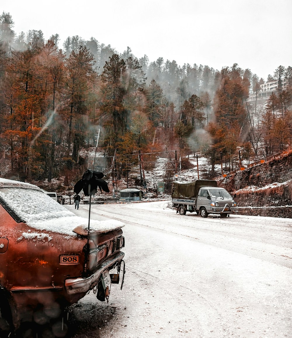 a red car parked on the side of a snow covered road