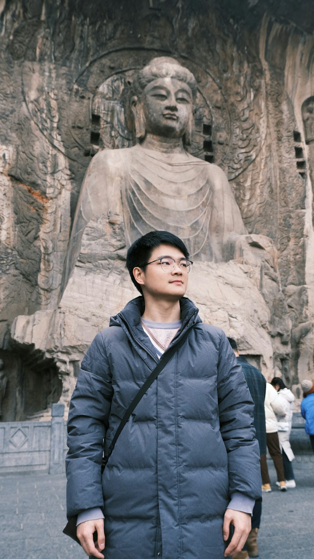 a man standing in front of a statue of buddha