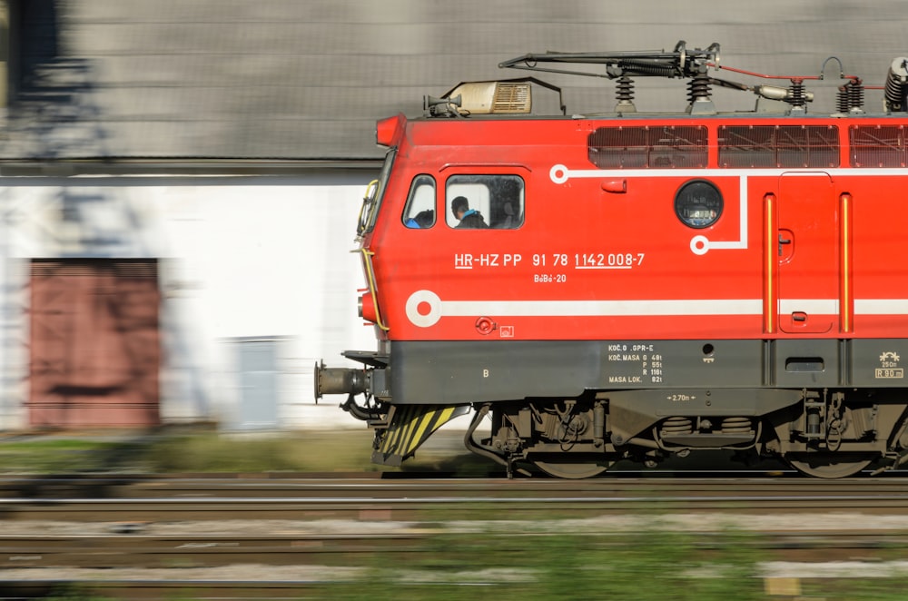 a red train traveling down train tracks next to a building