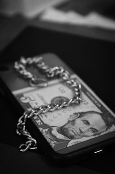 a black and white photo of a dollar bill on a chain
