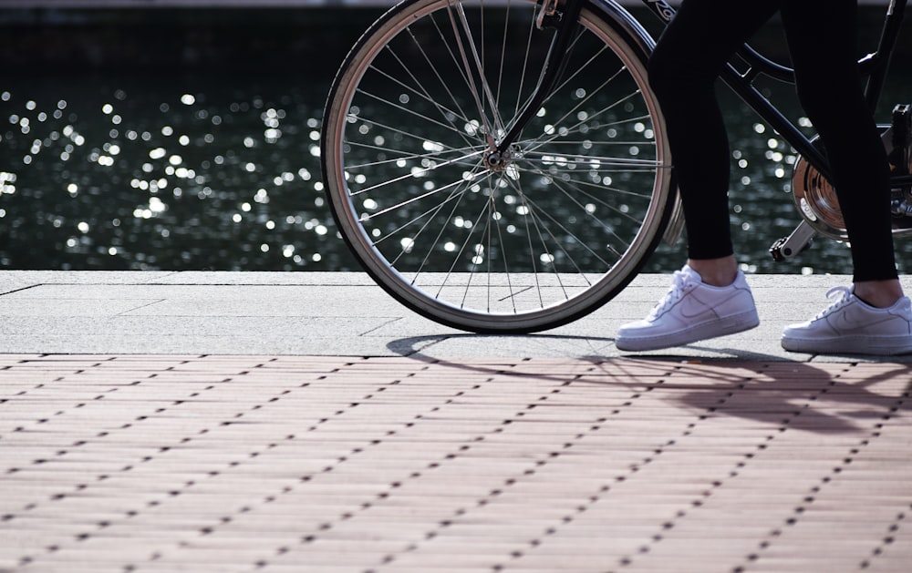 a person standing next to a bike on a sidewalk