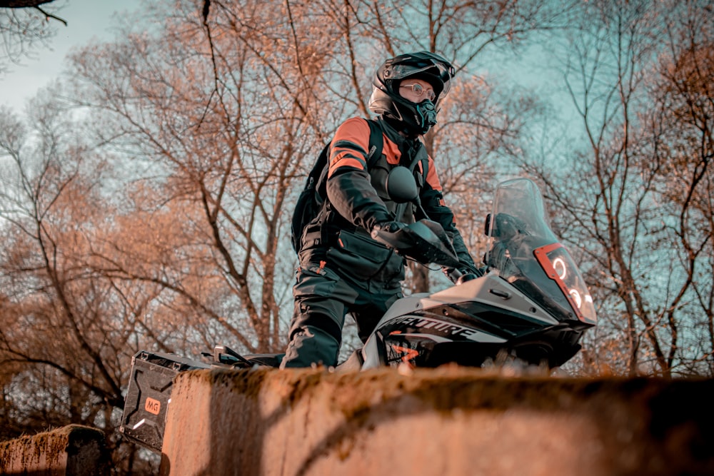 a man riding a motorcycle on top of a cement wall