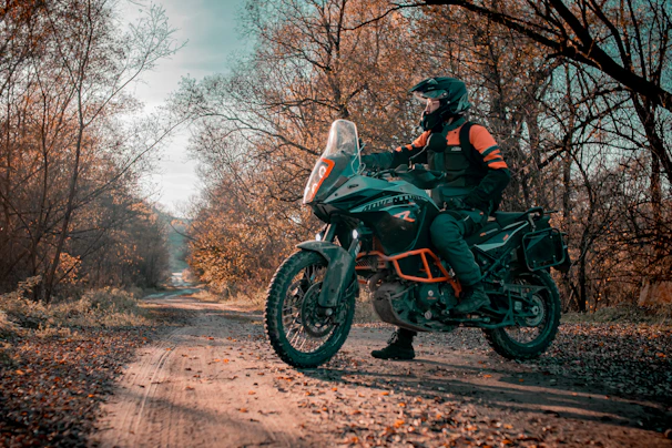 a man riding on the back of a motorcycle down a dirt road